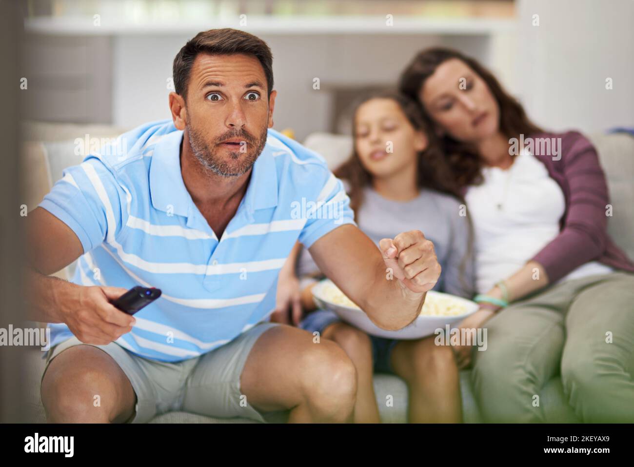 When theyre asleep, its sports time. a family sitting on the sofa at home. Stock Photo