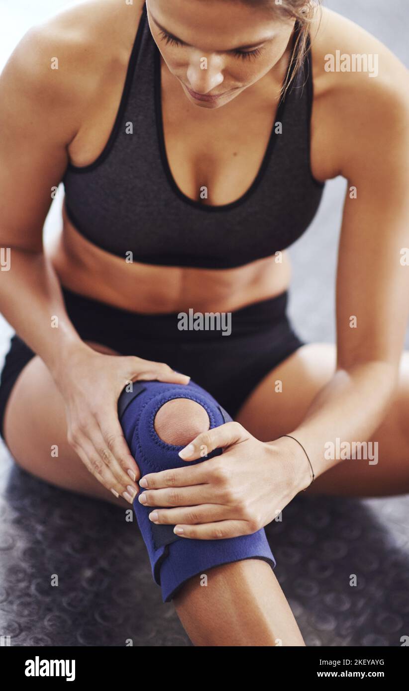 Overcome the pain...a sportswoman wearing a knee brace. Stock Photo