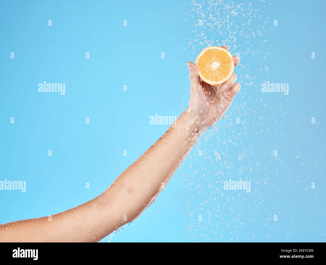 Lemon, water and hand of woman with fruit for health, beauty and wellness against blue mockup studio background. Cleansing, nutrition and person with Stock Photo