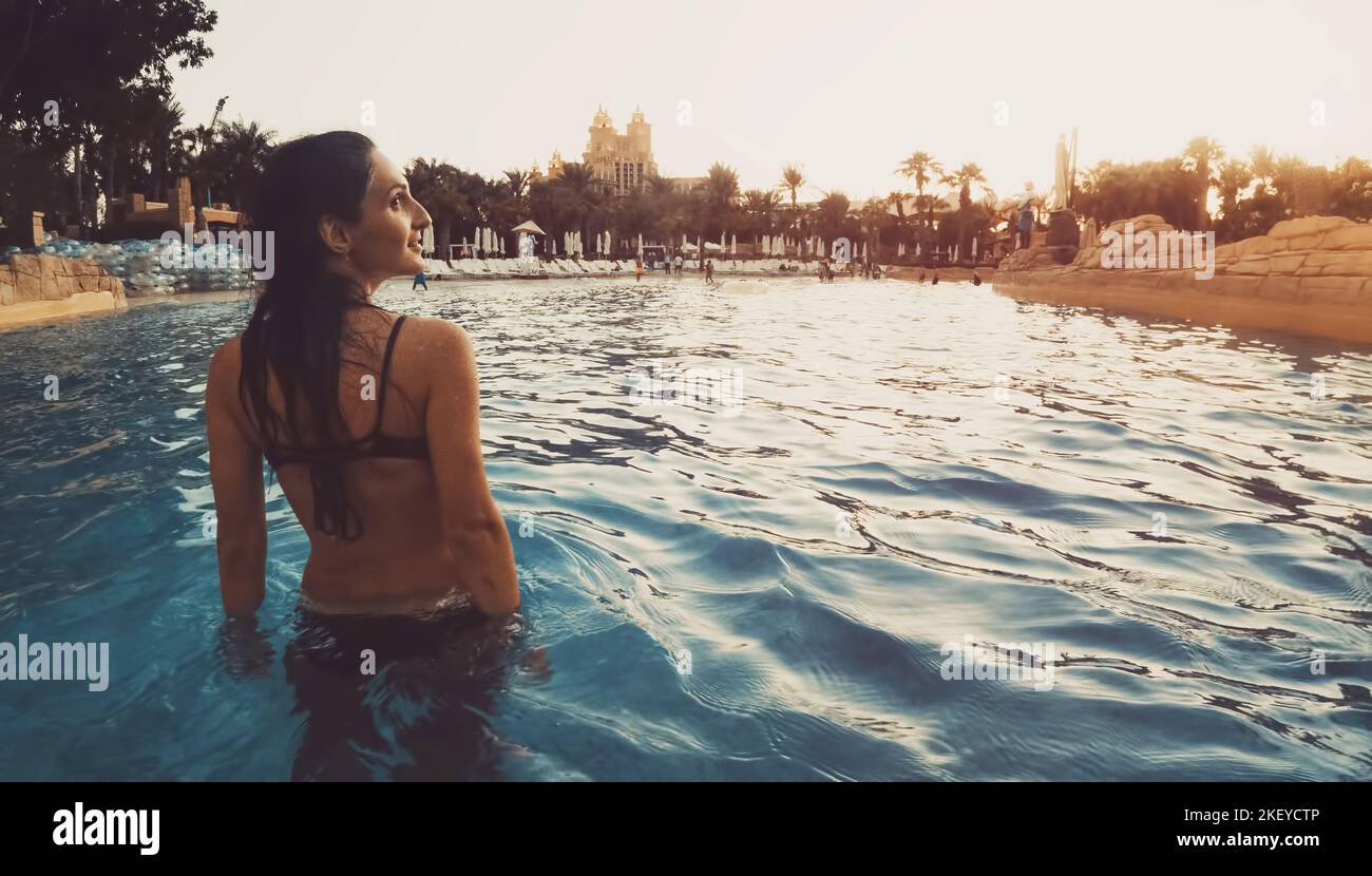 Aquaventure aqua park visitor woman walk enjoy sunset in pool with atlantis hotel water park park panorama Stock Photo