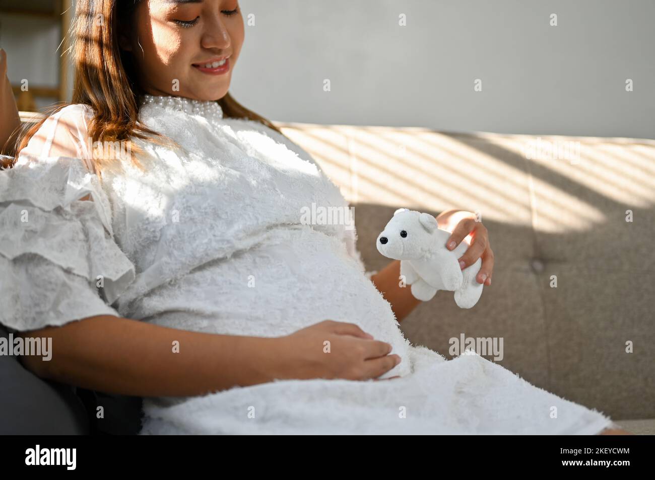 Happy and lovely Asian pregnant woman relaxing on sofa in the living