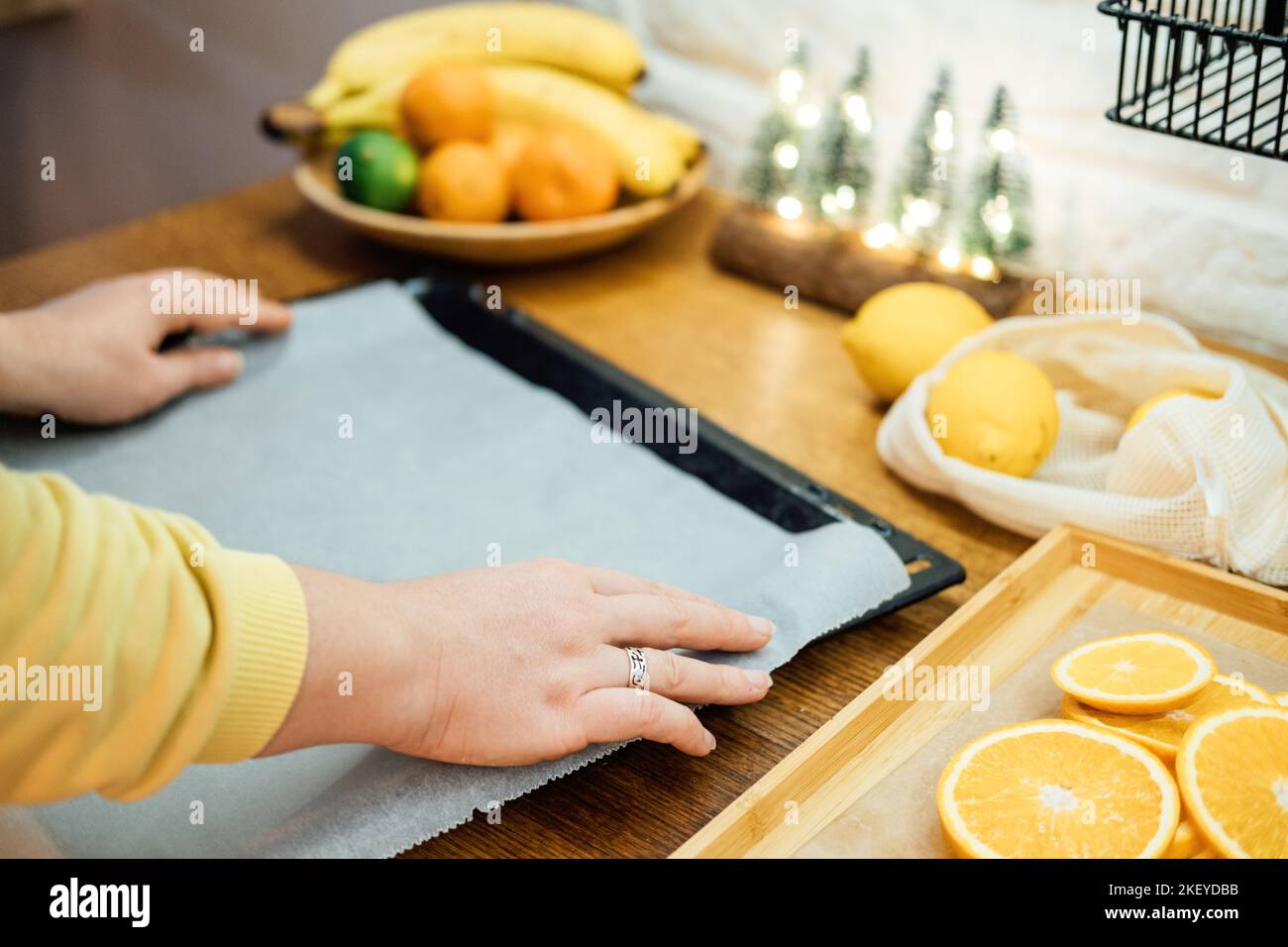 How to Dry Orange Slices for Eco friendly zero waste Holiday Decor. Close up Process of Drying Orange Slices in Oven. Woman cutting slices of orange Stock Photo