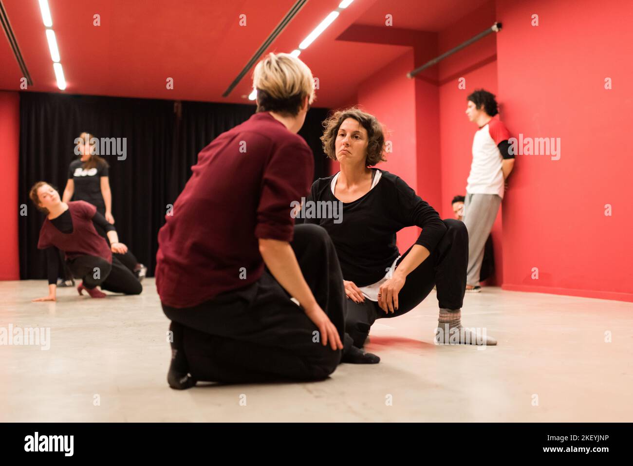 Two young women on their knees look at each other's faces with a sad expression, in a show of
