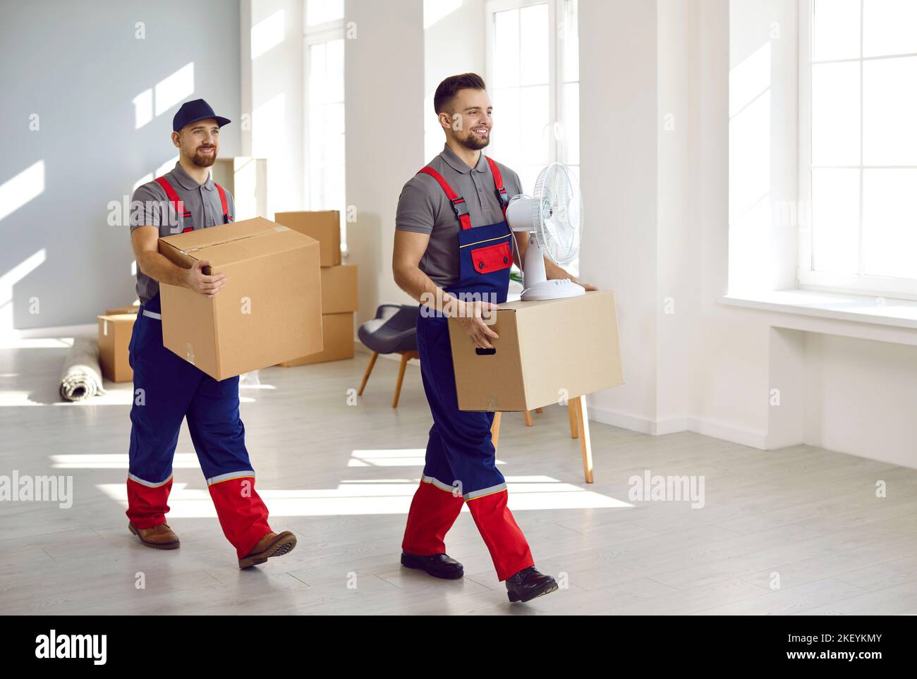 Young workers from moving company and delivery service removing boxes from apartment Stock Photo