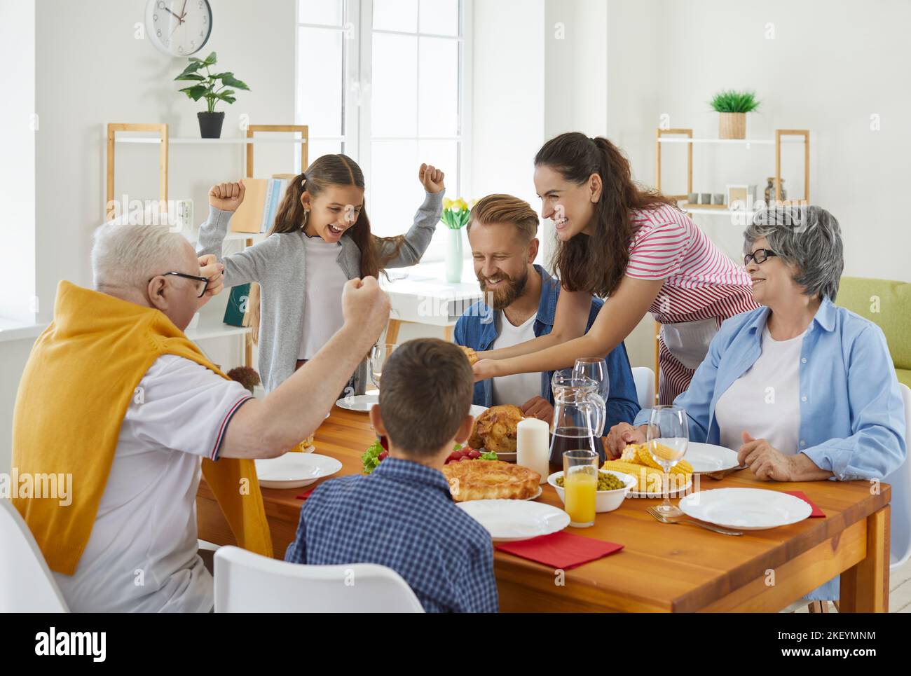 Happy joyful family sitting around table at home and having holiday meal all together Stock Photo