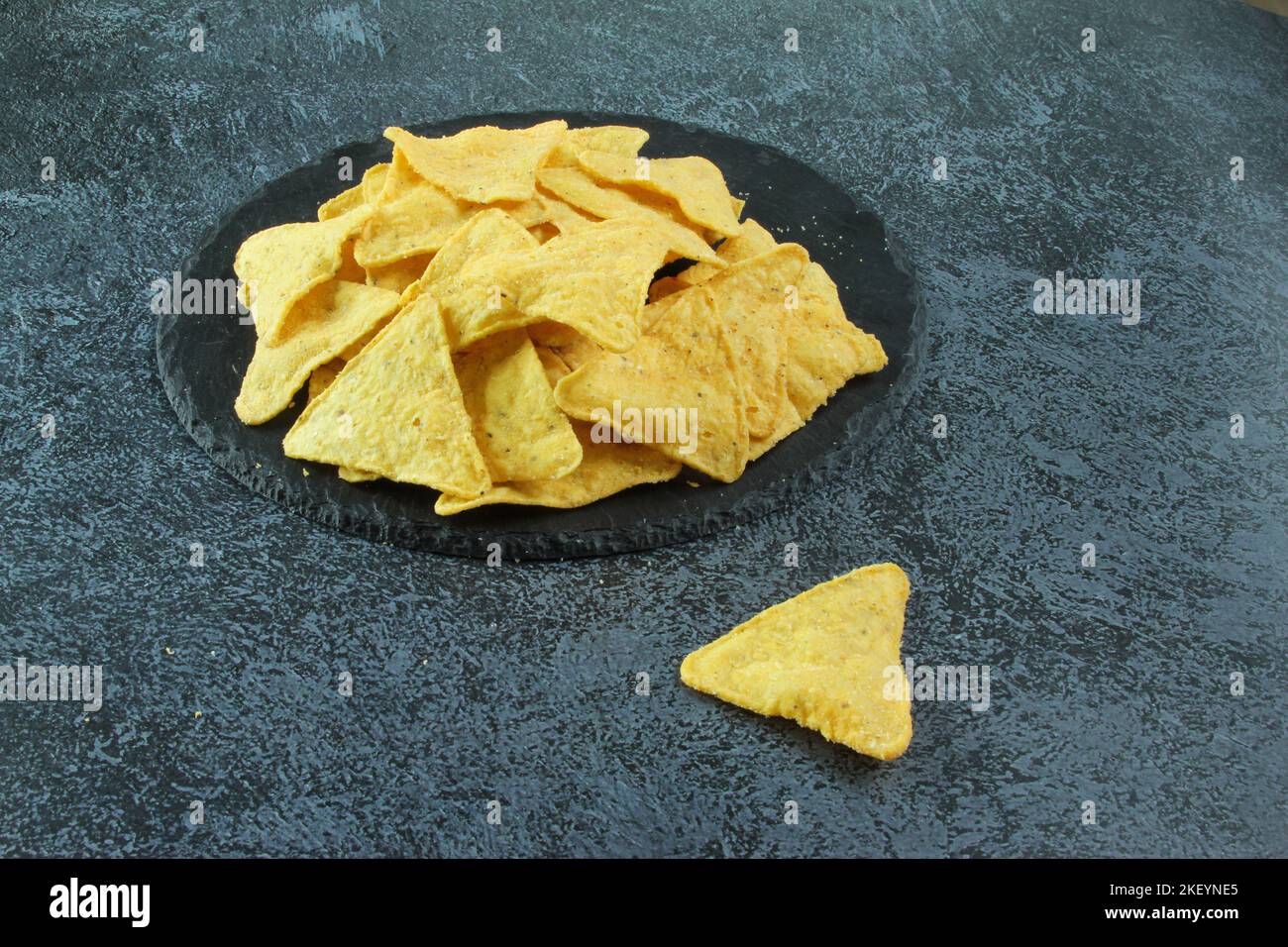 Mexican corn chips nachos on black stone or on the black concrete background. Stock Photo