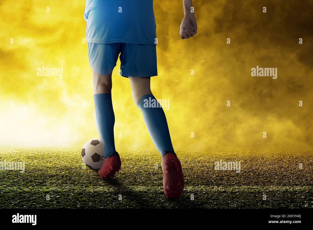 Rear view of a football player man in a blue jersey kicking the ball on ...