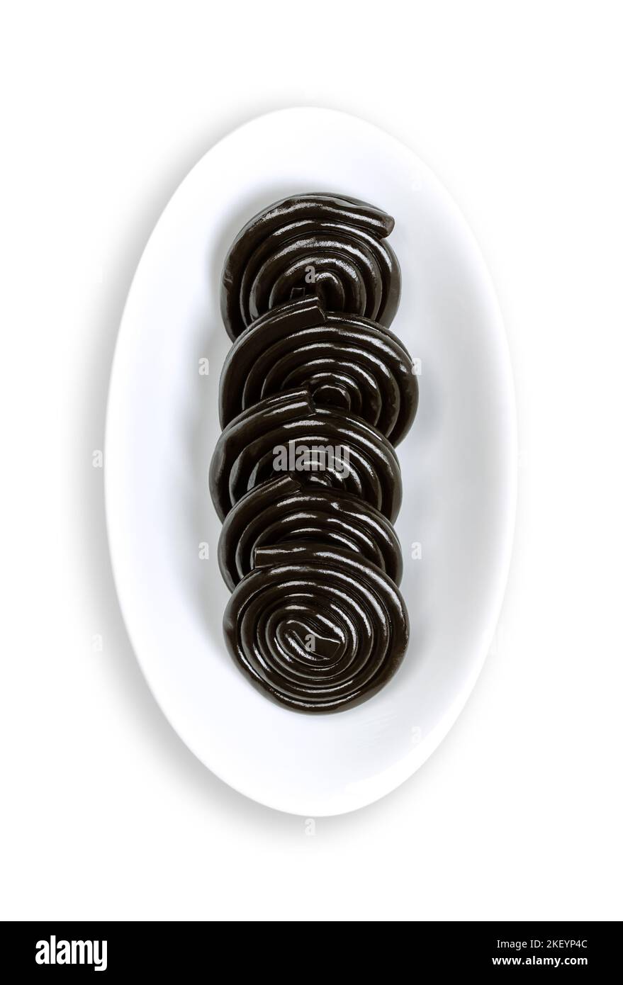 Liquorice wheels, in an oval white bowl. Licorice confection, usually flavored and colored black with the extract of the roots of the liquorice plant. Stock Photo