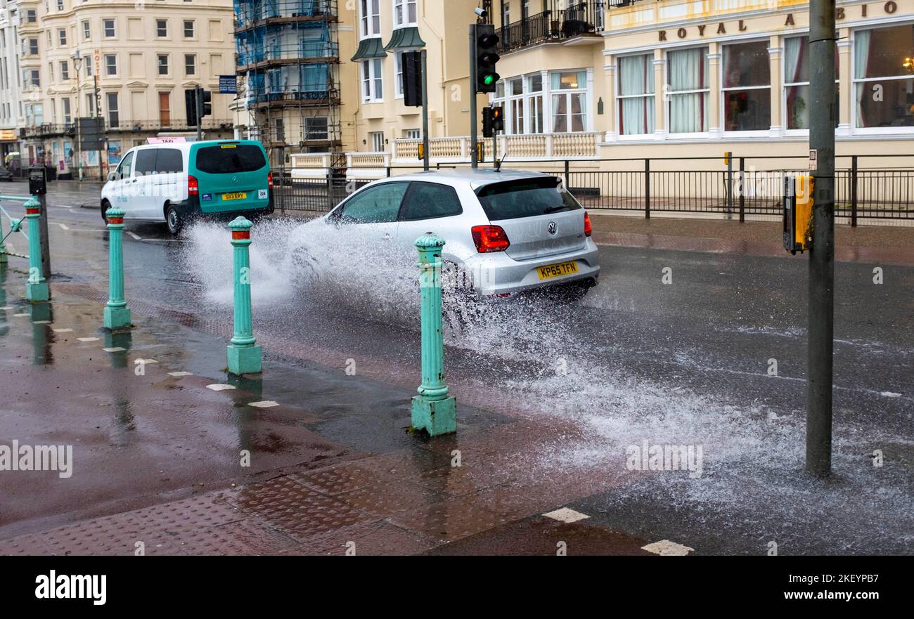 Brighton UK 15th November 2022 - Traffic passes through surface water along Brighton seafront during heavy rain and strong winds as storms sweep across the South Coast this morning : Credit Simon Dack / Alamy Live News Stock Photo
