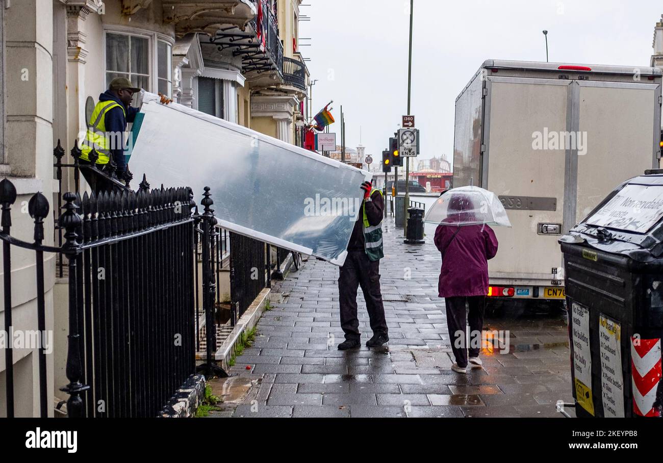 Brighton UK 15th November 2022 - Delivery workers carry on working in Brighton during heavy rain and strong winds as storms sweep across the South Coast this morning : Credit Simon Dack / Alamy Live News Stock Photo