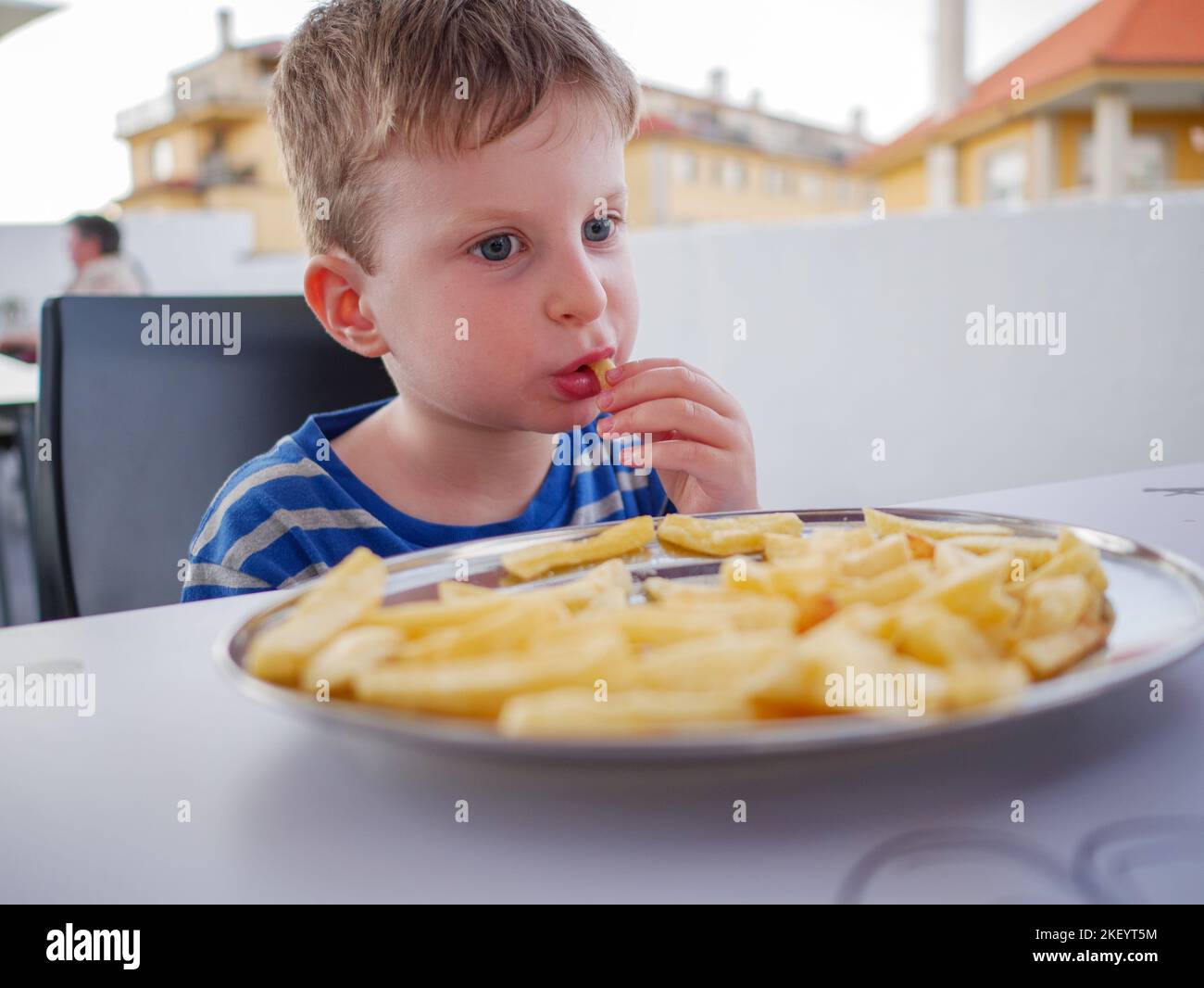 Young three year old boy eating fried chips Stock Photo