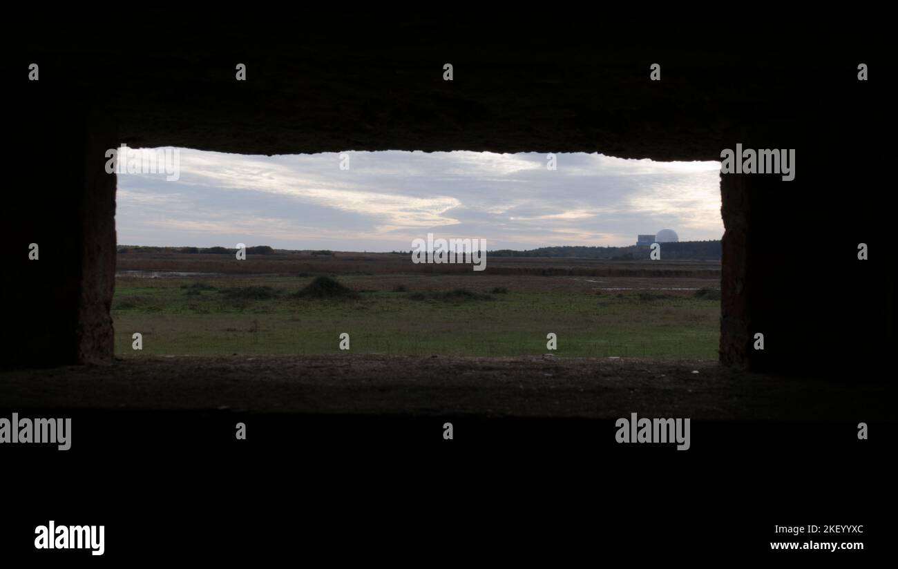 Sizewell B nuclear power station viewed through a loophole in a bunker (pillbox) built during WW2 in the ruins of Leiston Chapel, Suffolk, UK Stock Photo
