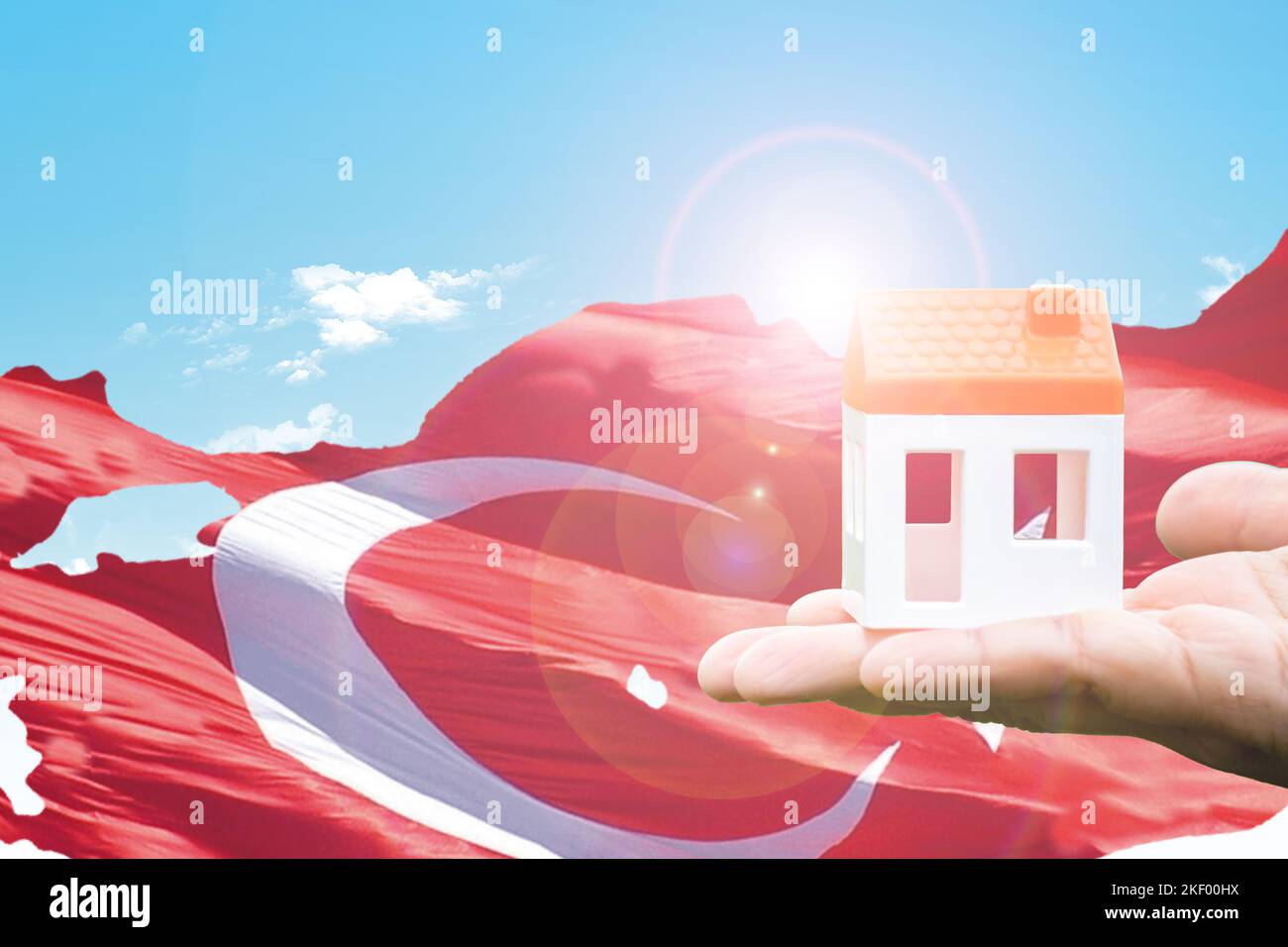 Real estate idea concept, Crisis of house prices for rent and sale in Turkey. In hands holding of a  house figure against the background of the flag. Stock Photo