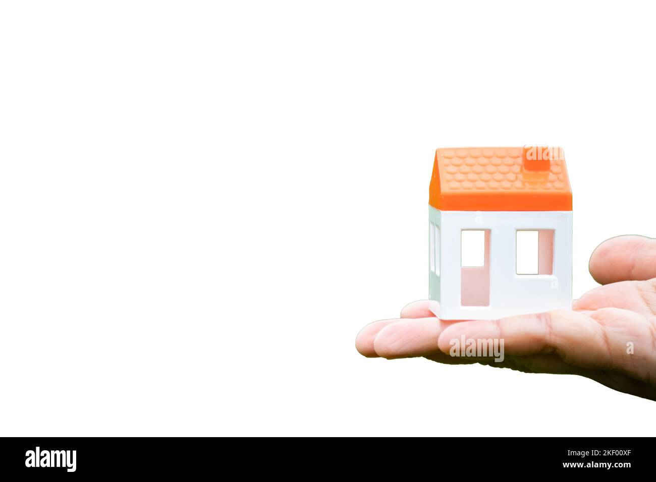 Hand holding house model or figure isolated in front of white background.  Real estate idea concept. Property and financial. Copy space. Stock Photo