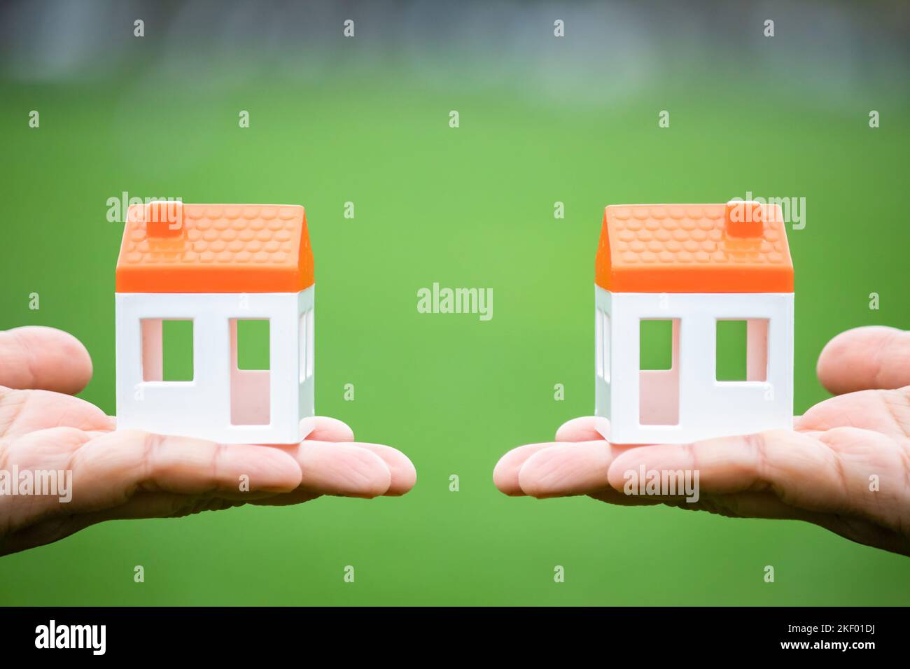 New home, right and left hand holding mutual house model isolated on green background. Real estate idea concept photo. For sale or rent. Investment. Stock Photo