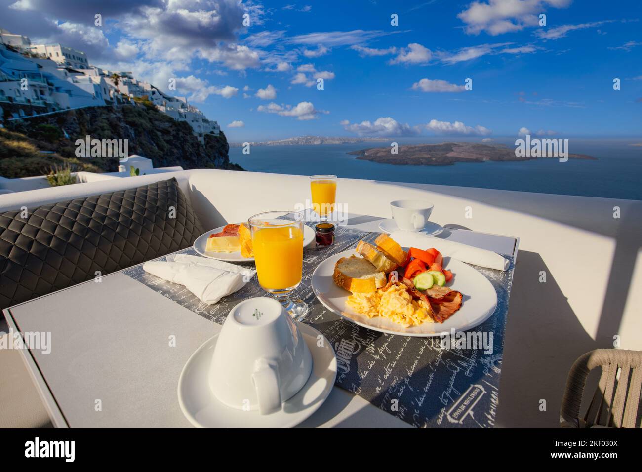 Breakfast time in Santorini in hotel. Luxury mood with fresh omelet and fruits with juice over sea view. Luxurious summer traveling holiday background Stock Photo