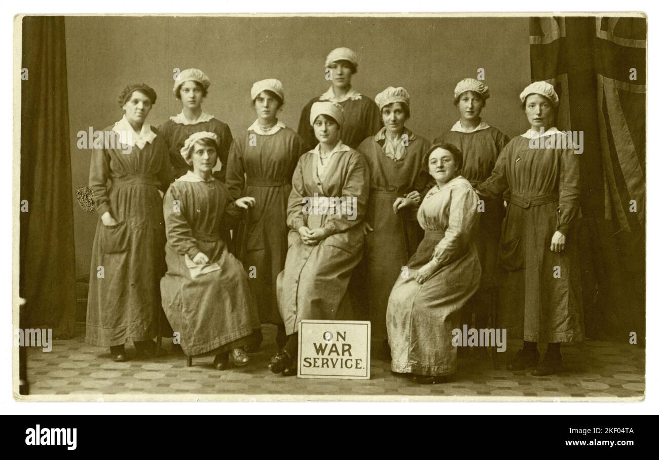 Original WW1 era postcard of female munitions workers, far RH girl has 'on war service' badge and there is an 'on war service' sign in front of them. From the photographic studio of Whyte and Sons, 20 Union St. Glasgow, Scotland, U.K. circa 1916-1918 Stock Photo