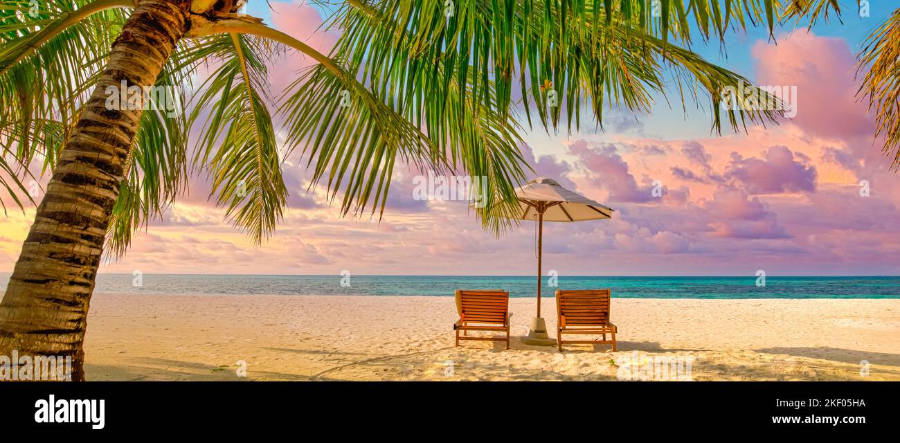 Amazing sunset beach. Romantic couple chairs umbrella. Tranquil togetherness love concept scenery, relax beach, beautiful landscape design. Getaway Stock Photo