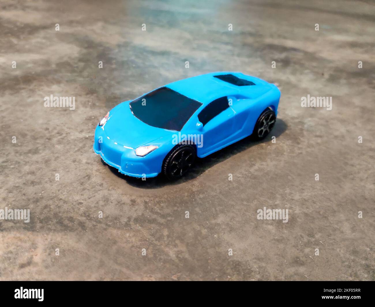 A vintage toy blue sports car resting on the ground. Stock Photo