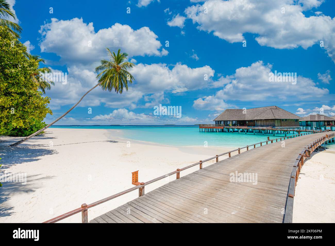 Overwater bungalow in the Indian Ocean. Pier palm trees white sand villas with amazing green lagoon scenic beach view. Picturesque travel landscape Stock Photo