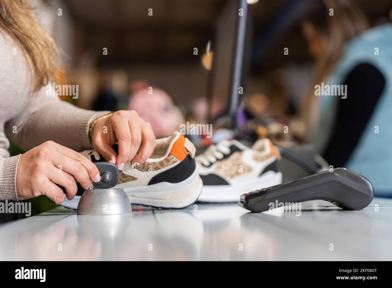 Clothing store clerk removing the alarm from a piece of clothing Stock
