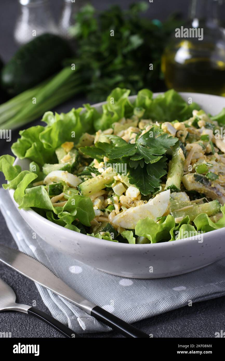 Salad with squid, cucumbers, boiled eggs and cheese in white bowl on green lettuce leaves Stock Photo