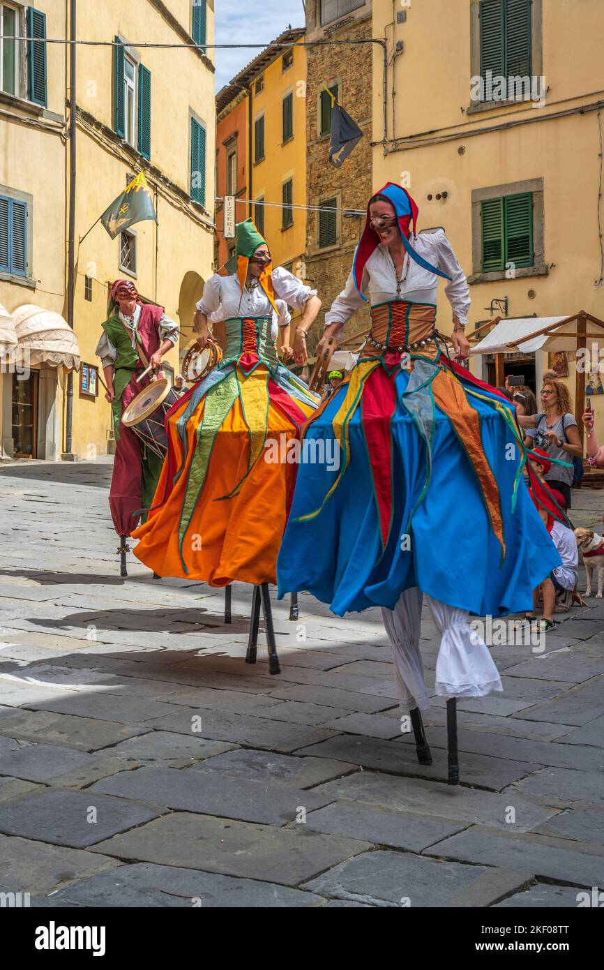 Street performers on stilts on Piazza Luca Signorelli in hilltop town of Cortona in Tuscany, Italy Stock Photo