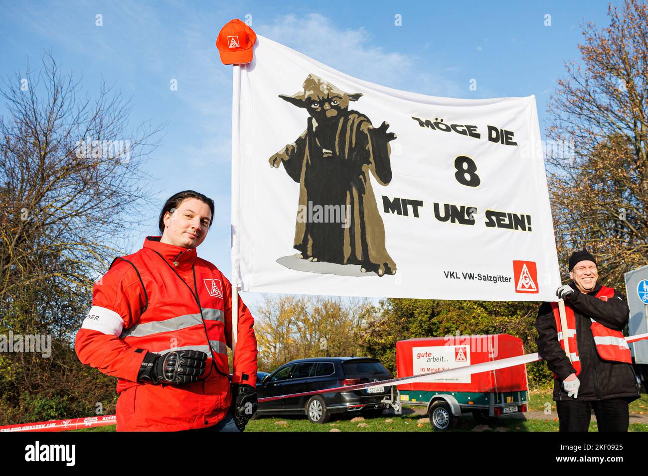 Salzgitter, Germany. 15th Nov, 2022. Two rally participants for the warning strike hold a banner with the inscription 'May the 8 be with us!' and a picture of 'Yoda,' a character from the 'Star Wars' film series. The collective bargaining talks, which have been ongoing since September, were adjourned last week after the fourth round without result. IG Metall is demanding eight percent more money for employees in the metal and electrical industry. Credit: Michael Matthey/dpa/Alamy Live News Stock Photo