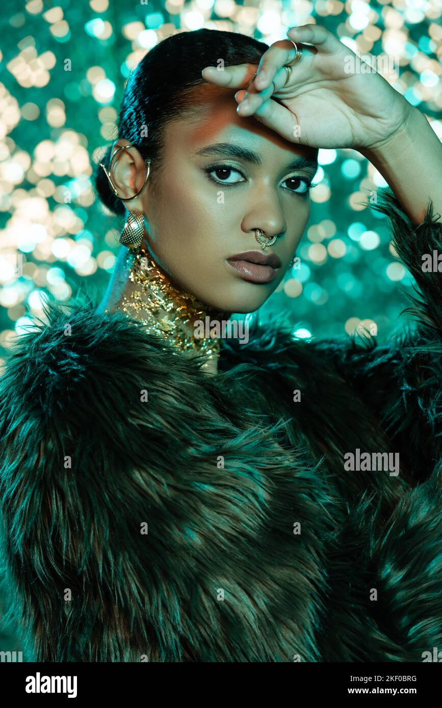Stylish african american woman in faux fur jacket looking at camera on ...