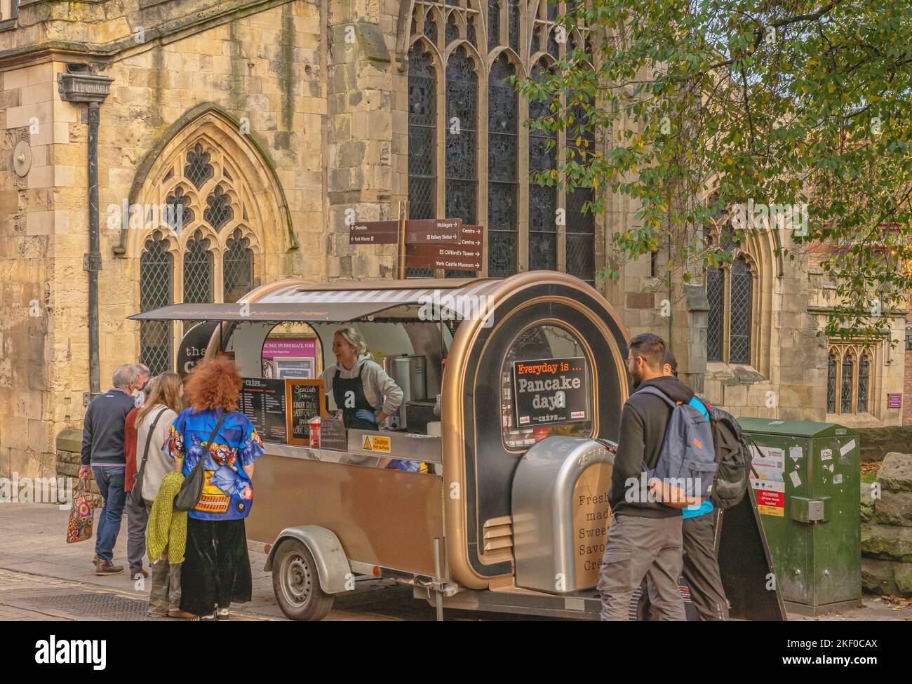 A pedestrianised city street. A trailer serving pancakes is positioned ...