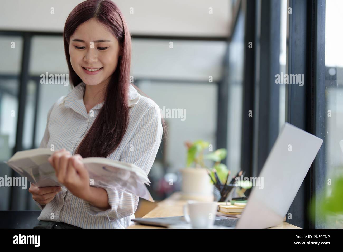 Portrait of an Asian woman reading a book during her lunch break Stock Photo