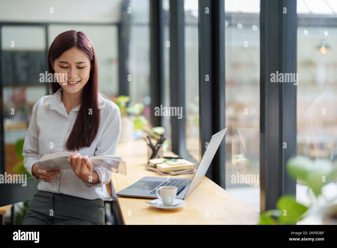 Portrait of an Asian woman reading a book during her lunch break Stock Photo