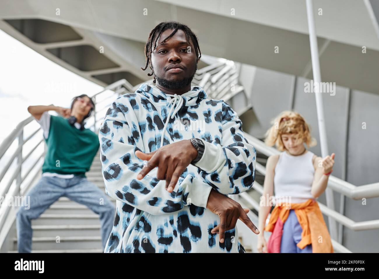 Diverse group of young people dancing outdoors and wearing street style clothes focus on black man in foreground Stock Photo