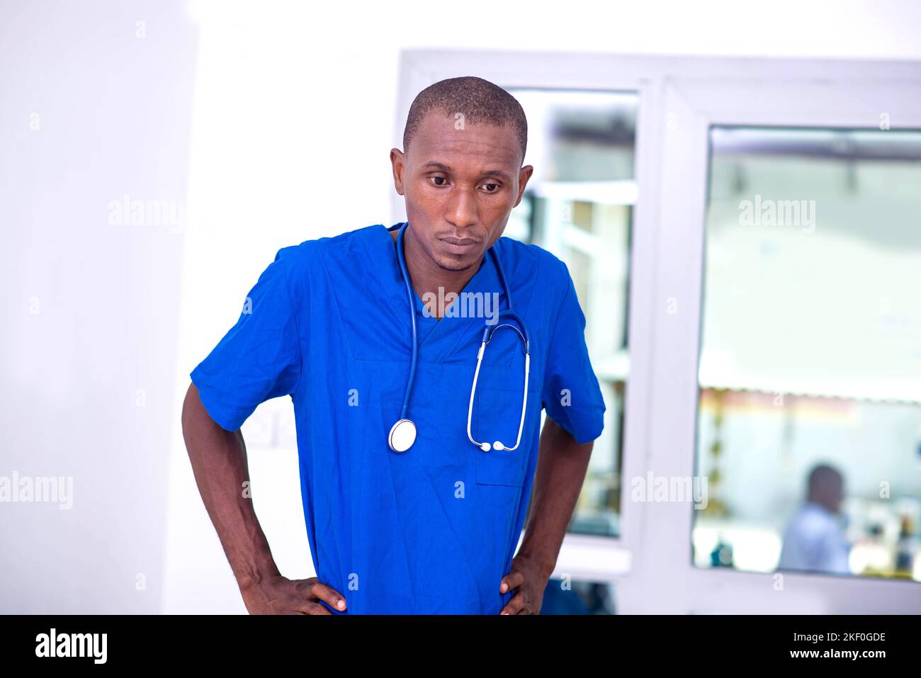 portrait of young male doctor wearing blue uniform at hospital, having problems. Stock Photo