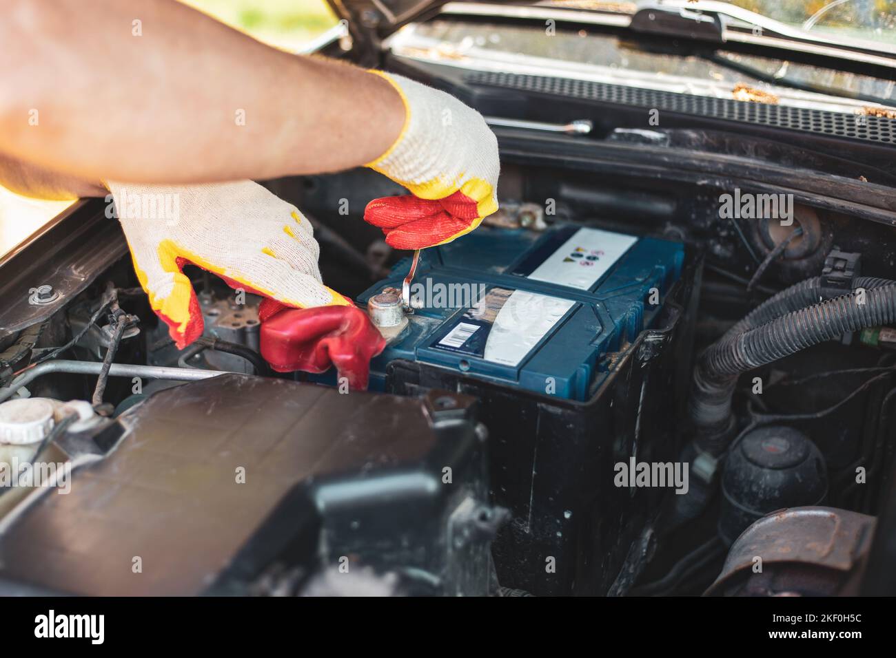 An auto mechanic is repairing a car. Removing the battery Stock Photo