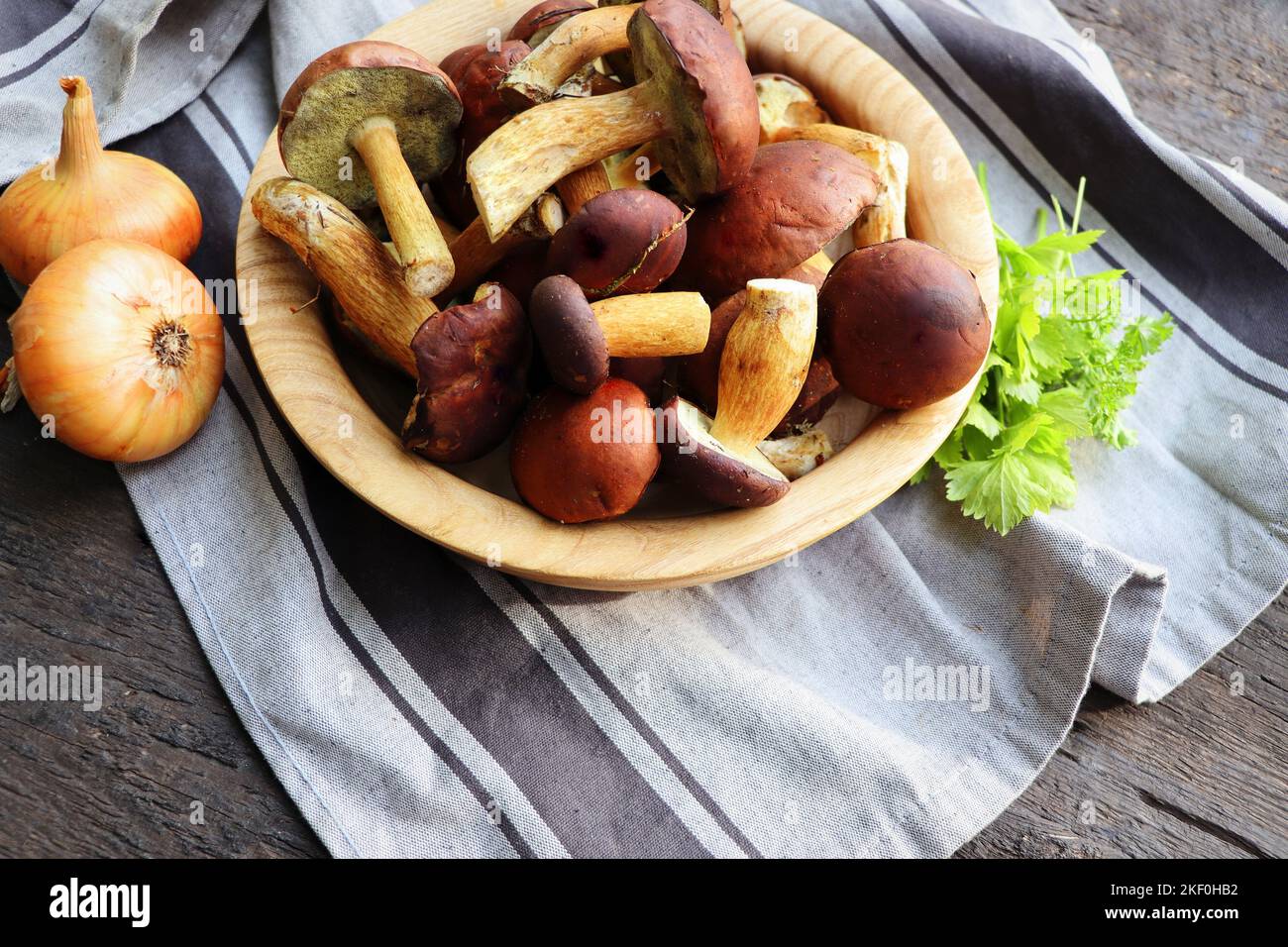 Forest boletus mushrooms on rustic wooden background in wooden bowl and herbs Stock Photo