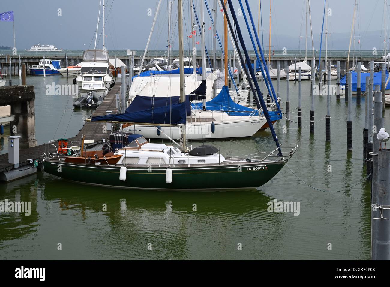 Sailing yachts arranged in rows in a marina partly covered for winter season and with lowered sails. Stock Photo