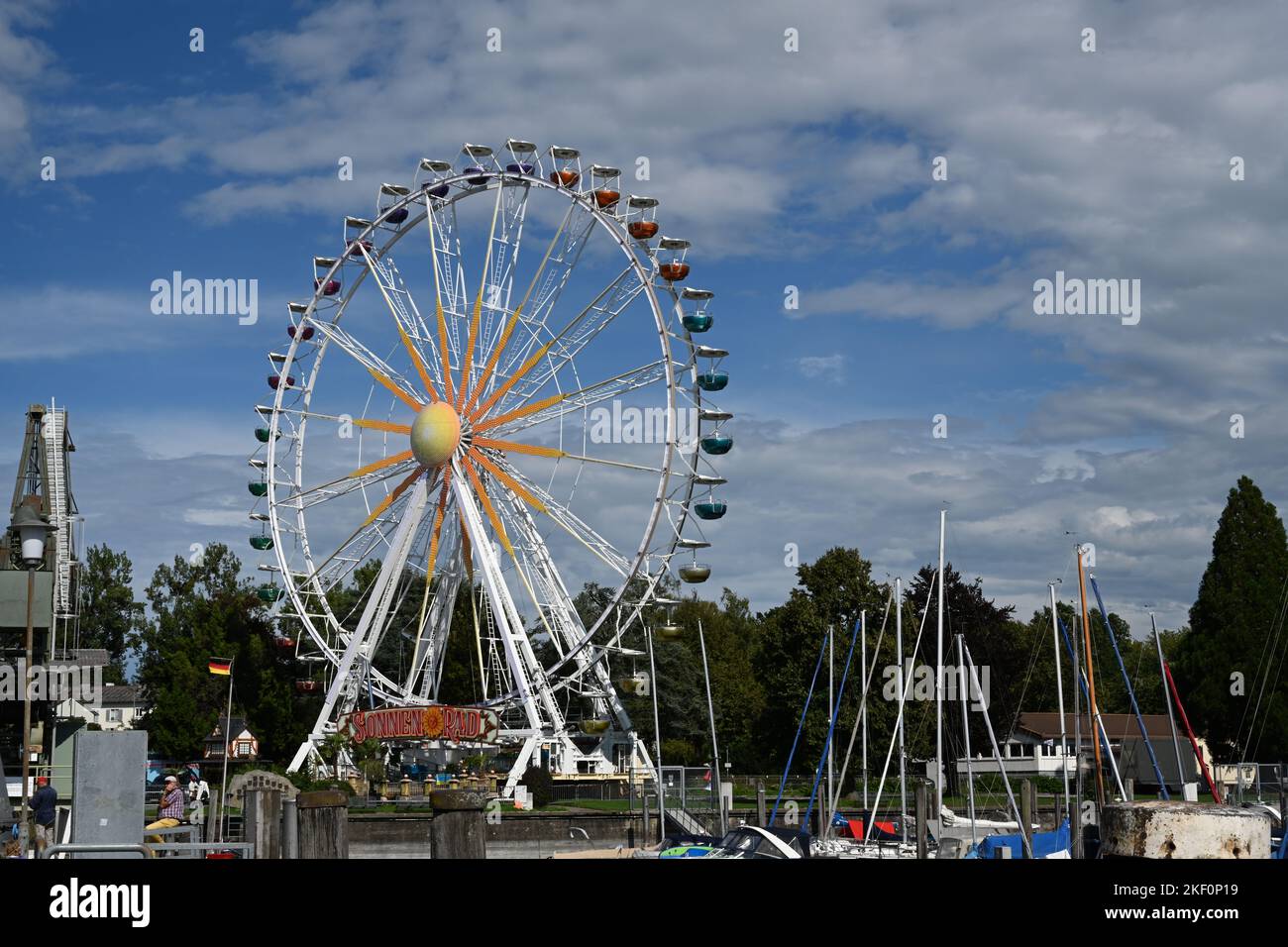 Ferris wheel situated in marina of Friedrichshafen. In foreground are anchored boats and yachts. Stock Photo