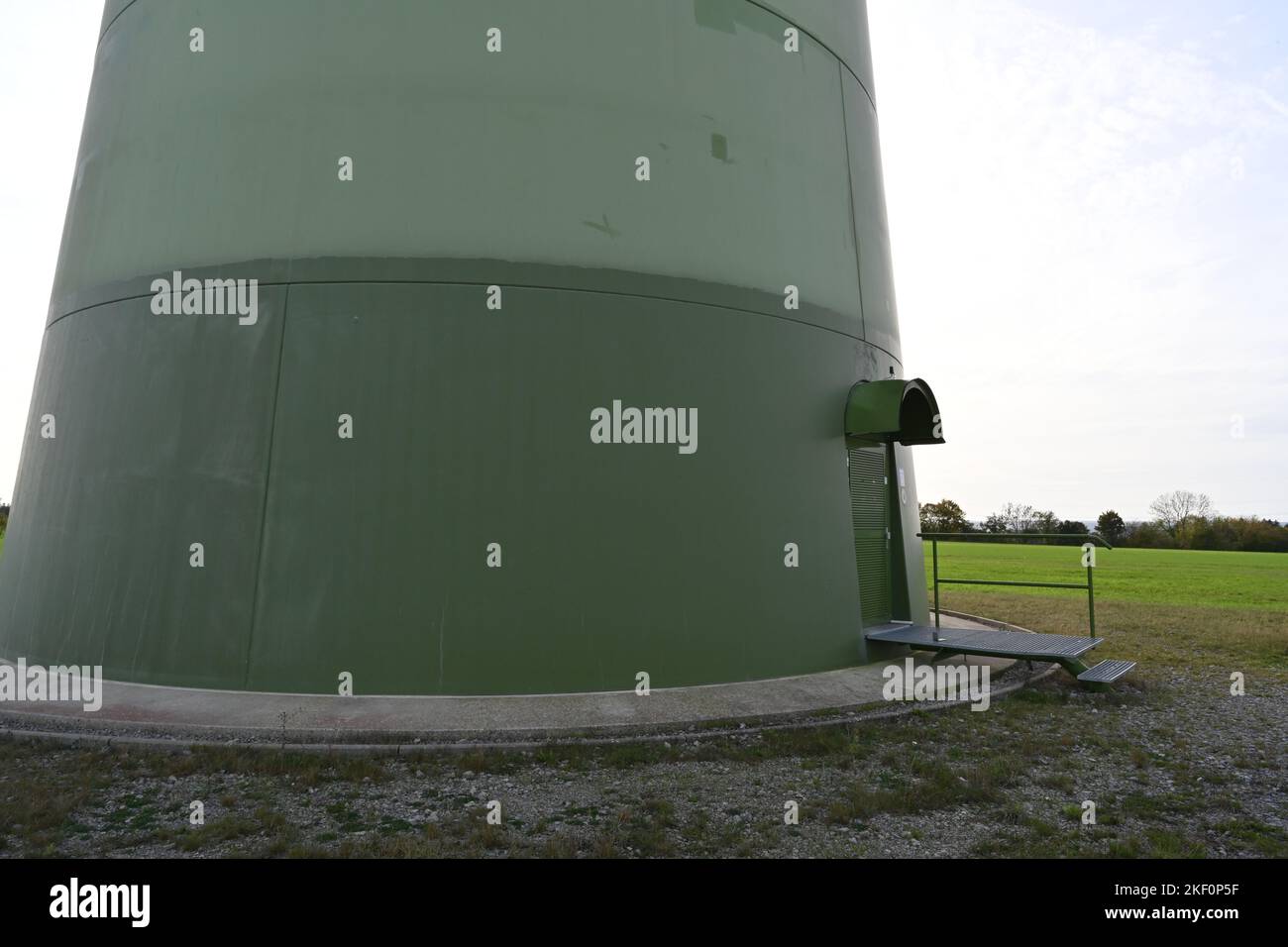 View on green base of round column with door of on-shore wind turbine supplying with renewable energy the needs of inhabitants. Stock Photo