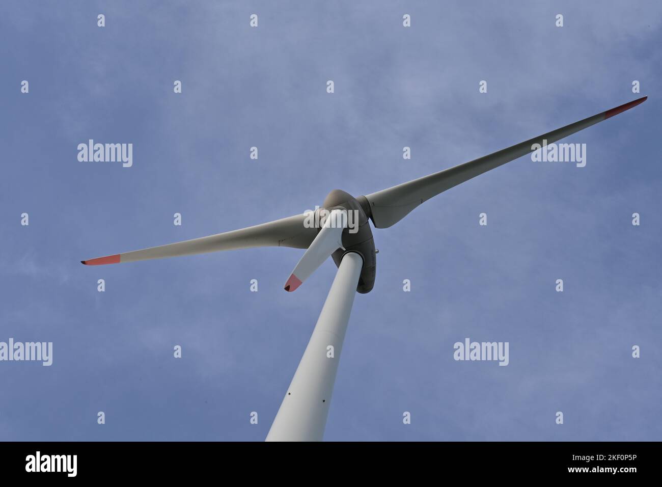 Detail view on propeller of on-shore wind turbine against blue sky supplying with renewable energy the needs of inhabitants. Stock Photo