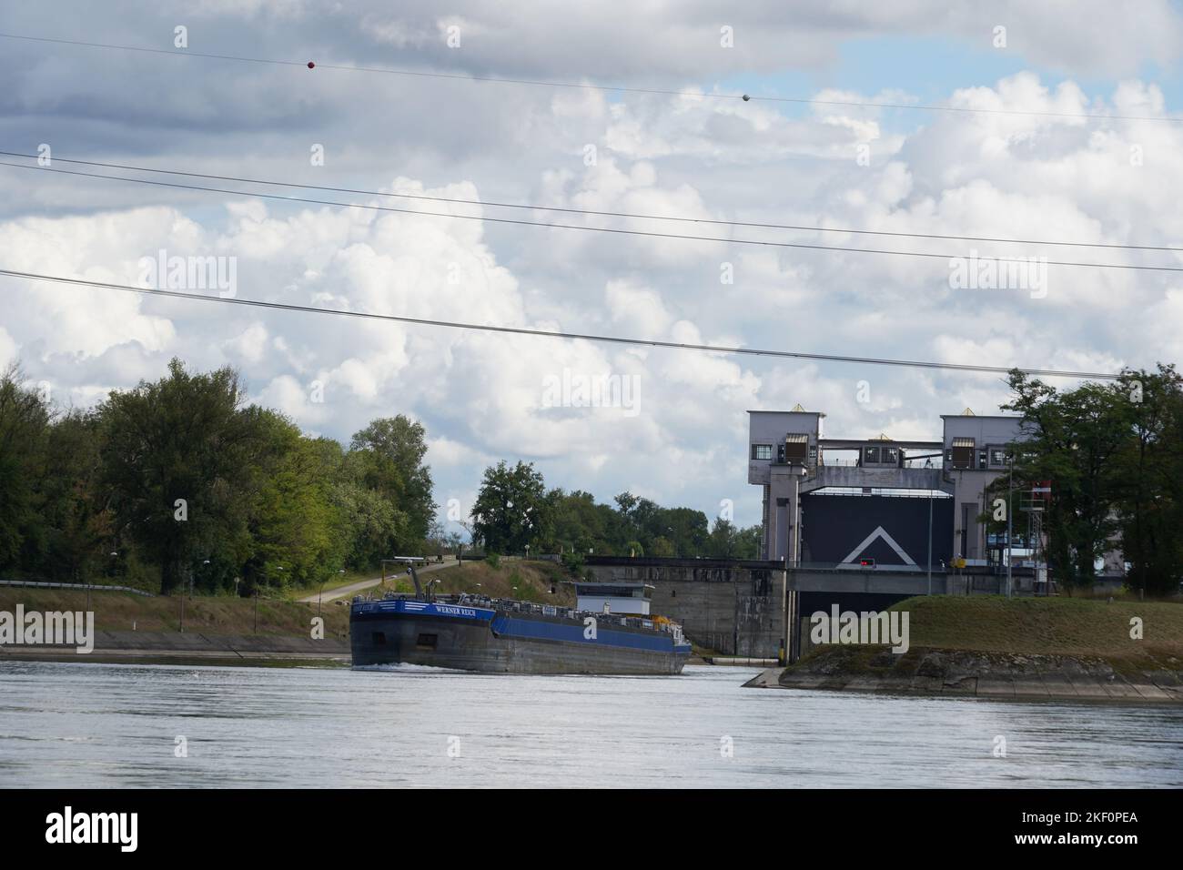 River barge is sailing outside from the lock with open gate. Stock Photo
