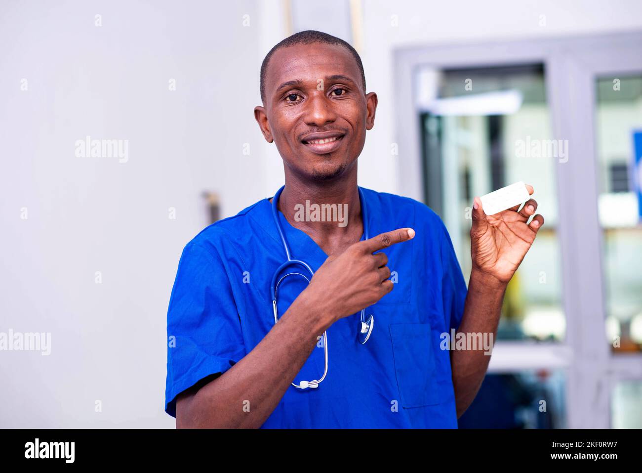 young male doctor in blue uniform with stethoscope pointing finger at ...
