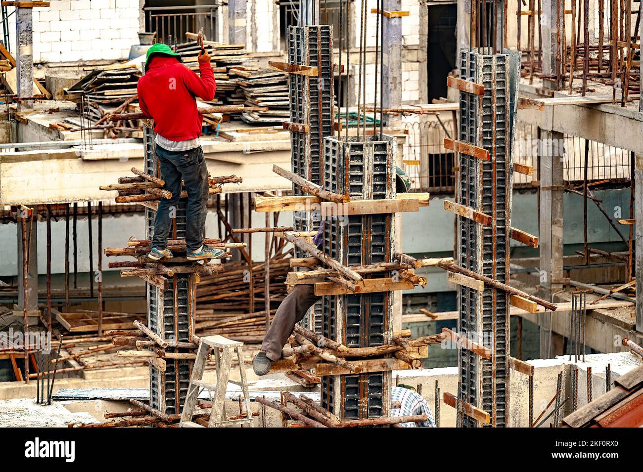 A construction worker nails wood poles as temporary supports to steel