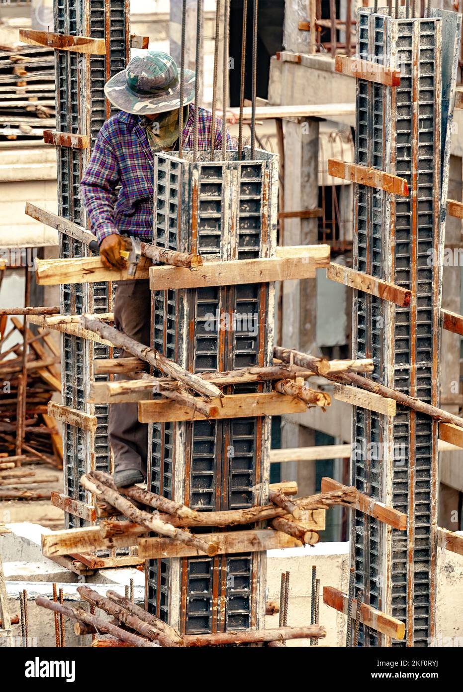 A construction worker nails wood poles as temporary supports to steel