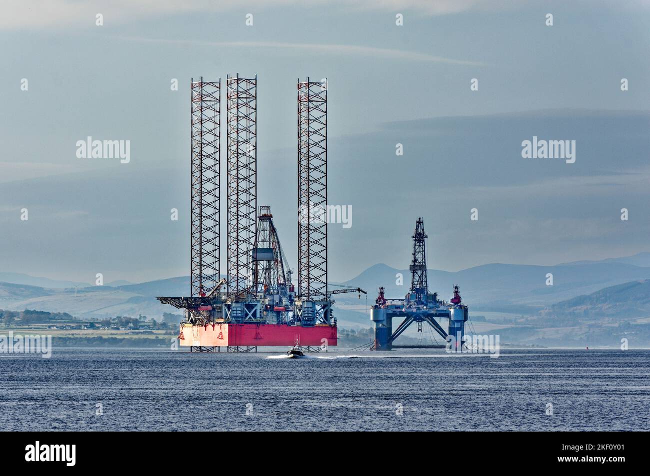 Cromarty Firth Scotland small Pilot boat passing decommissioned oil rigs Stock Photo
