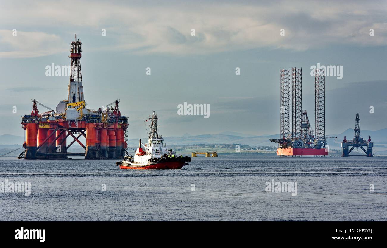 Cromarty Firth Scotland tug boat Strathdon passing in front of the orange oil rig Transocean Leader Stock Photo
