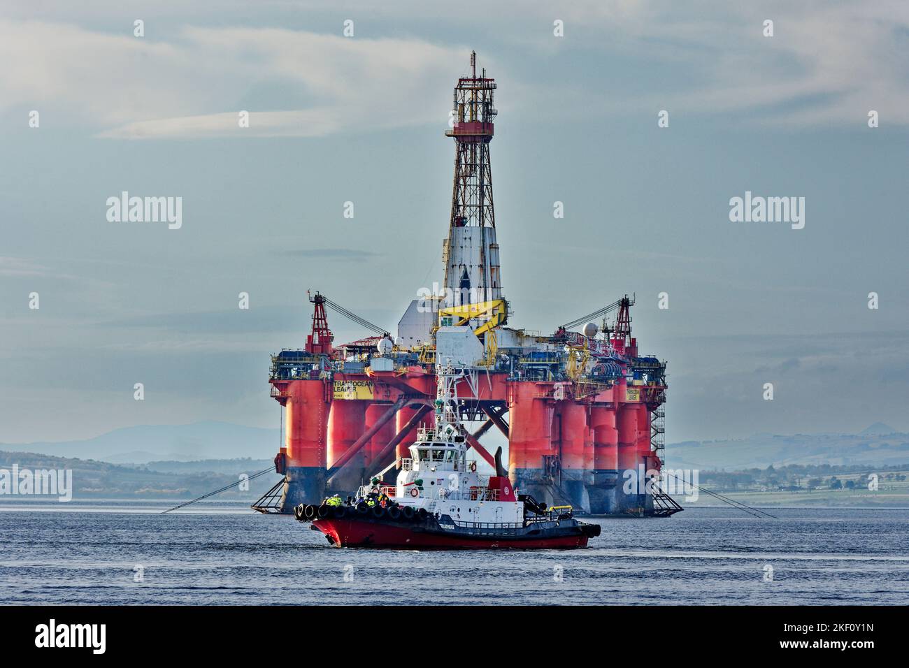 Cromarty Firth Scotland tug boat Strathdon sailing in front of the orange oil rig Transocean Leader Stock Photo