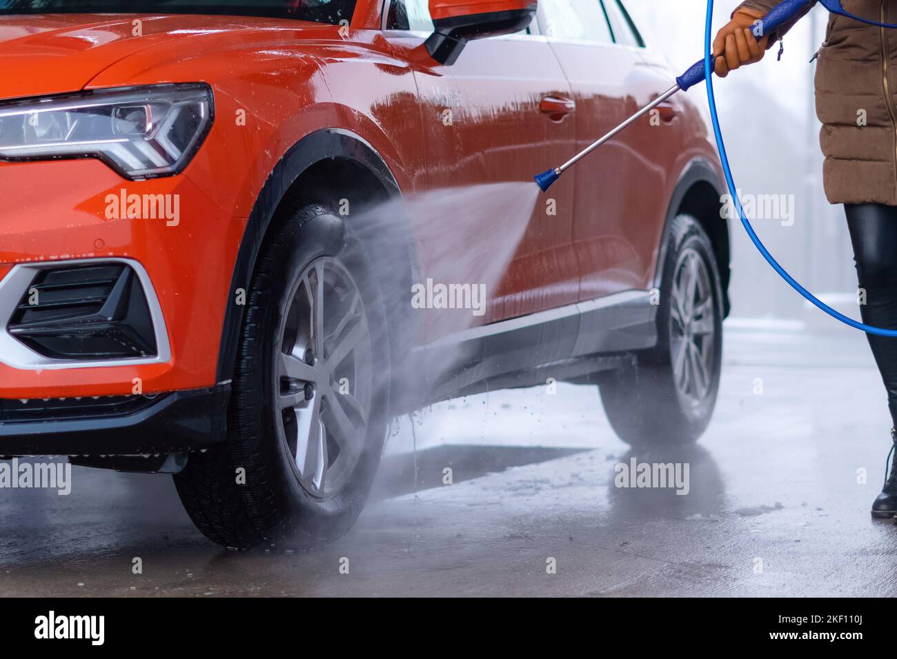 Close up of woman washing the car with high pressure water at self