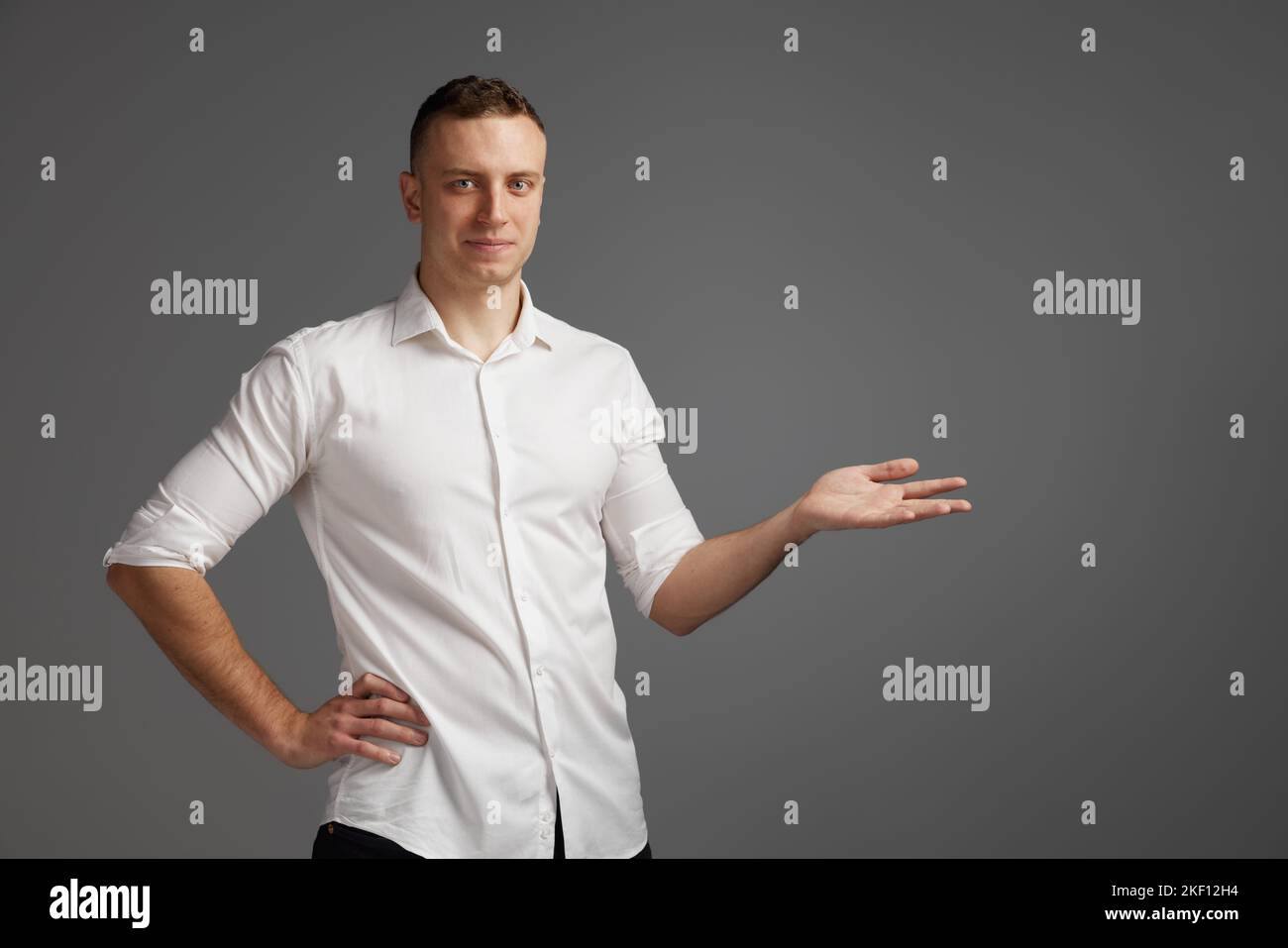 Portrait of young man posing in white shirt isolate dover grey studio ...