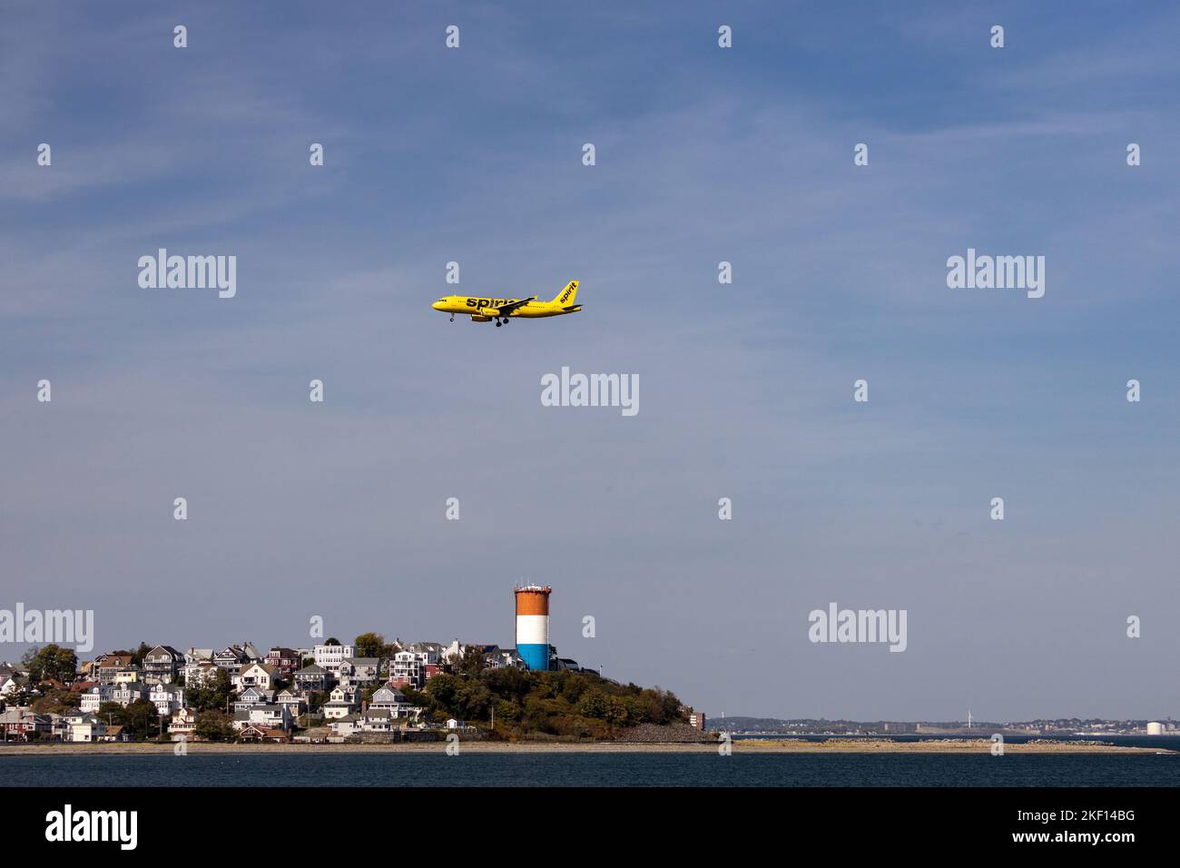 A Spirit Airlines plane flying over a beach before landing in Boston Stock Photo